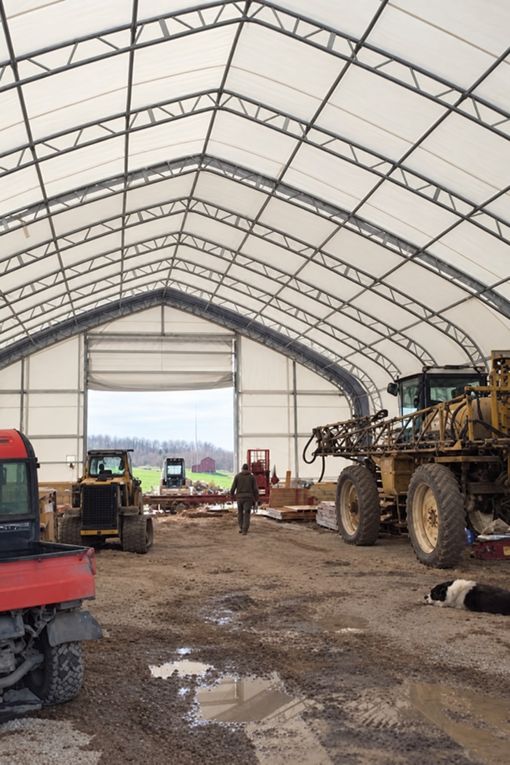 Farm machinery standing inside a covered fabric building