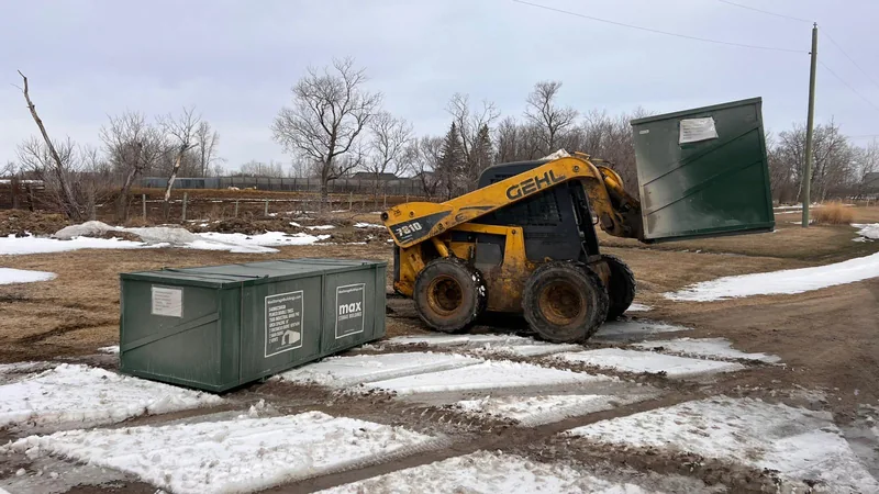 Skid steer handling a green MAX building-component crate