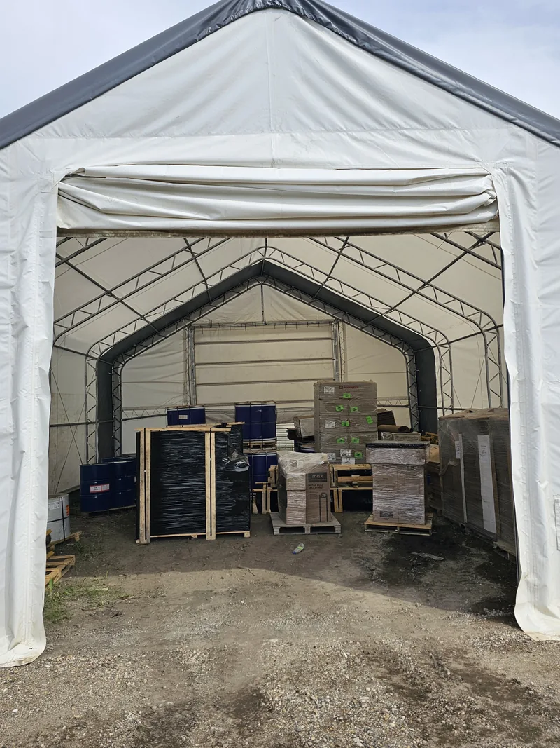 Open fabric-building entrance with pallets and stored materials inside