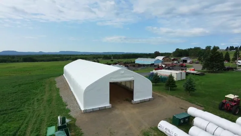 Drone view of the open entrance of a white fabric building on a farm
