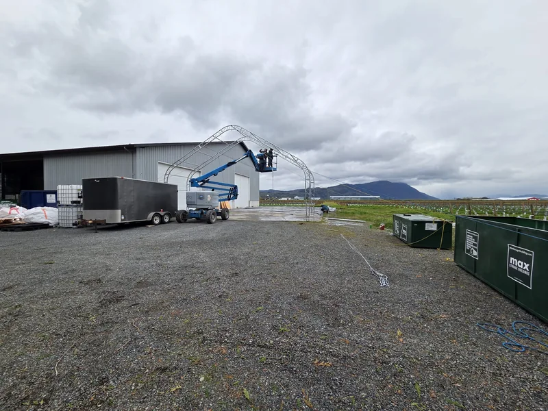 Building components and a boom lift in the yard beside a metal building