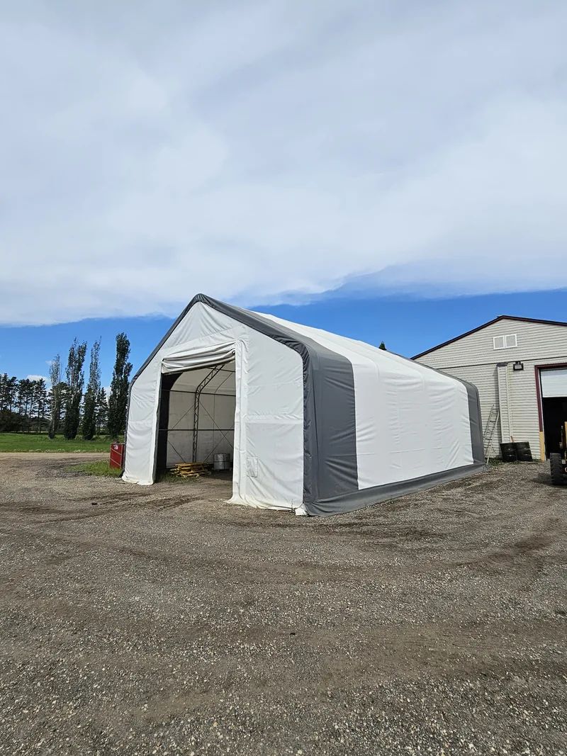 White fabric building with grey trim beside an existing workshop